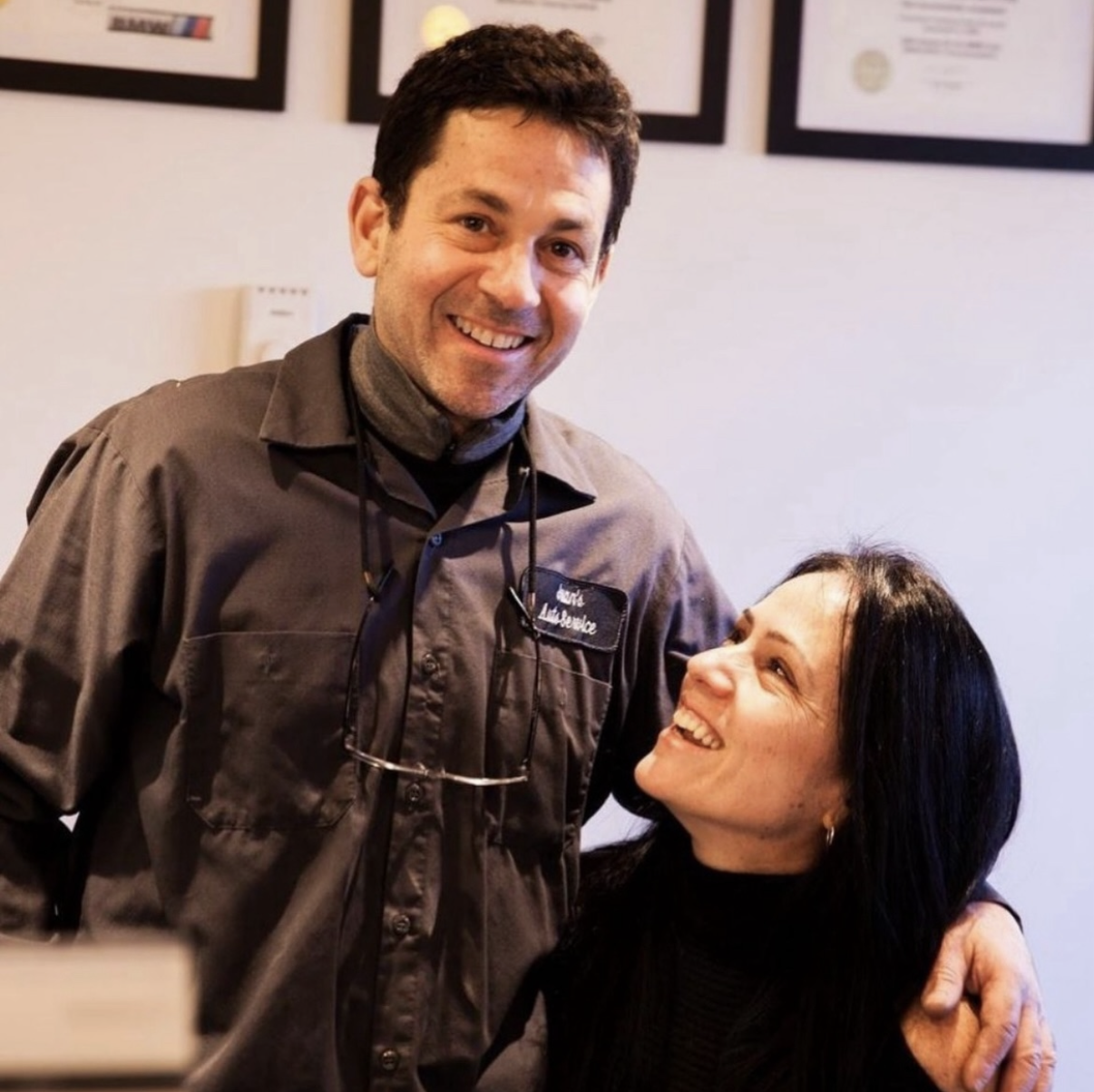 Juan and Stephanie smiling at the front desk of their River Road shop